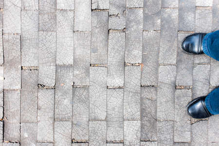 Two feet in hipster boots and jeans standing on an unusual grunge wooden brick floorの写真素材