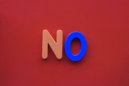 The word 'no' spelled in children's magnetic letters on a red backgroundの写真素材