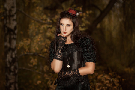 Portrait of a girl in a black dress of gothic stile with a clock on a chain
