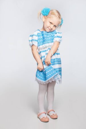 Cute little blonde girl on a white background shyの写真素材