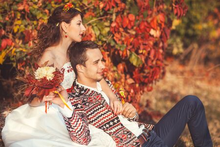 Portrait of bride and groom in autumn park they sit on the grass in autumn park bride groom huggingの写真素材