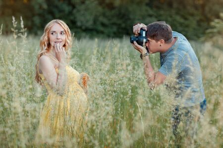 Beautiful pregnant girl stands in a field with a toy in his hands. Her photographs the photographerの写真素材