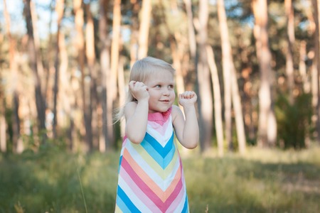 Little girl blonde child a colorful dress in the forest.の写真素材
