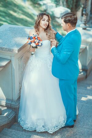 Newlyweds look at each other. Groom holds his bride's handの写真素材