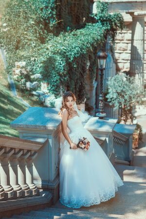 Beautiful bride with bouquet in hands standing on the stairsの写真素材