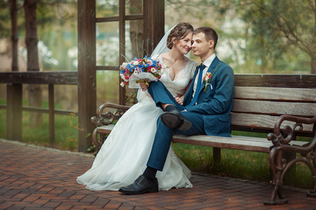 Bride and groom sitting together on a bench in the parkの写真素材
