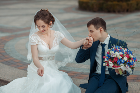 Groom holds a bouquet and kissing the hand of  brideの写真素材