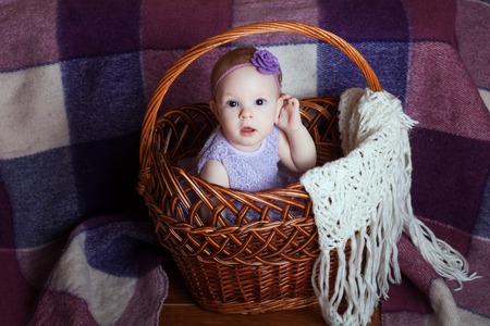 Beautiful baby girl in a wicker basketの写真素材