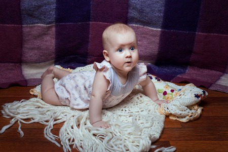 Beautiful baby girl lying on her stomach and looking aheadの写真素材