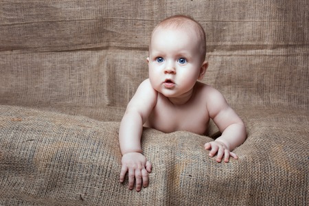 Charming baby girl with blue eyes on a beige backgroundの写真素材