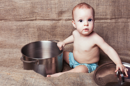 Child girl sits and exploring a pan with surpriseの写真素材