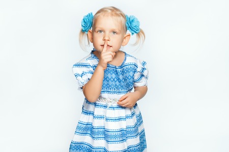 Beautiful baby girl on a white background making shhの写真素材