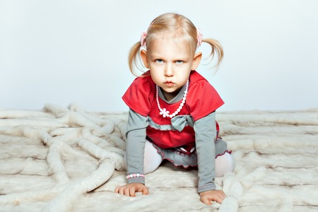 Baby blonde girl is on all fours and grimacesの写真素材