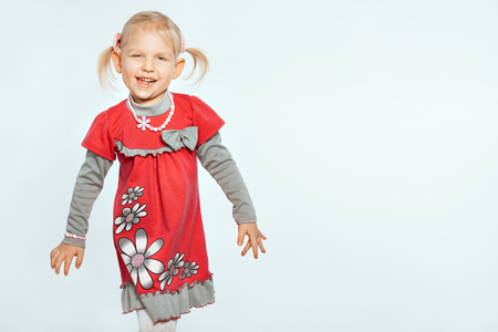 Beautiful baby girl on a white background. Girl goes and grimacesの写真素材