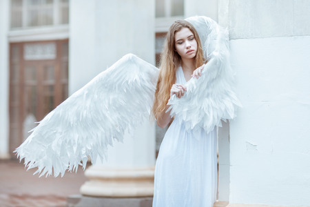 Young woman with white wings is standing near the column. The girl hid wingの写真素材