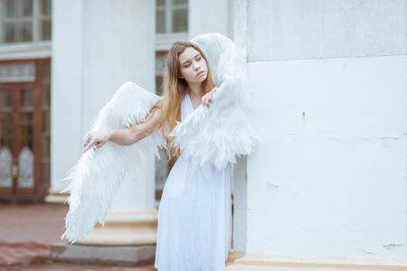 Young blonde girl with white angel wingsの写真素材