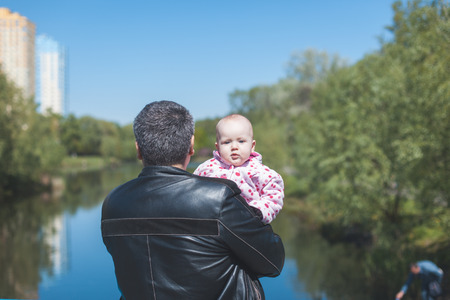 Dad with a child near the river. Dad standing with his backの写真素材