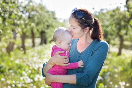 Young mother is in the garden with a babyの写真素材