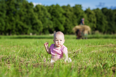 Beautiful baby girl sitting in the grassの写真素材