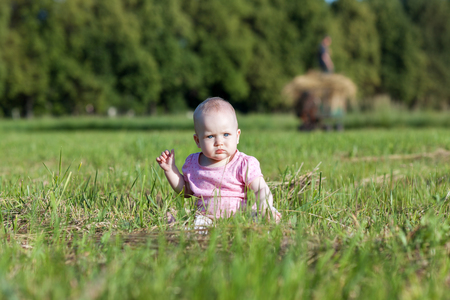 Beautiful baby girl sitting in the green grassの写真素材