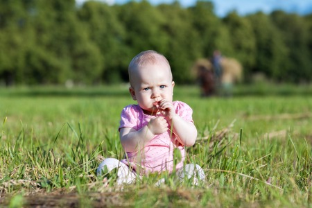 Little girl sitting in the grass on the fieldの写真素材
