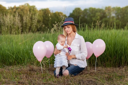 Mother and daughter sitting in a meadow among the pink balloonsの写真素材