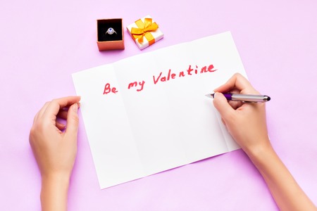 Female hands sign a letter of congratulations on Valentine's Dayの写真素材
