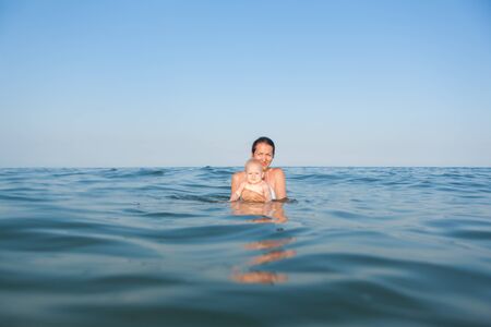 Mom and daughter in the water in the seaの写真素材