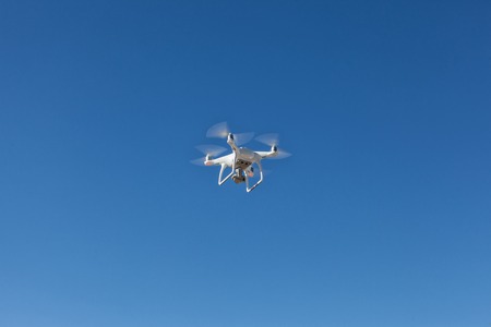 Quadrocopter unmanned camera hovers in bright blue skyの写真素材
