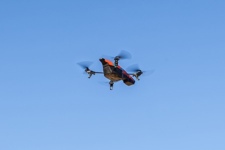 Red quadrocopter flying high in the skyの写真素材