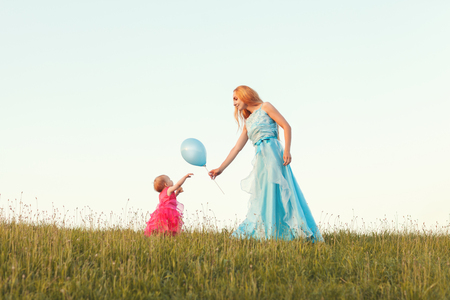 Young blonde woman giving her daughter a balloonの写真素材