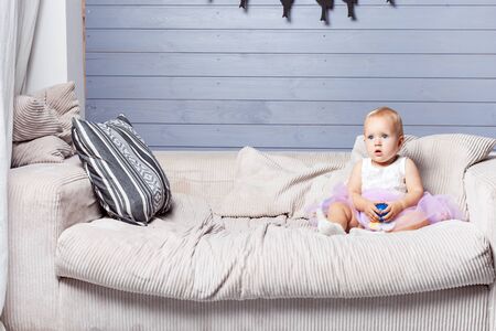 Child girl sitting on the couch and holding a small ballの写真素材