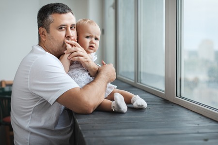 Little girl and her dad near the windowの写真素材
