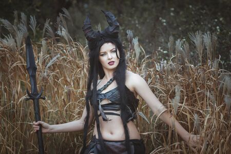 Beautiful wild girl with horns stands in the thicketsの写真素材