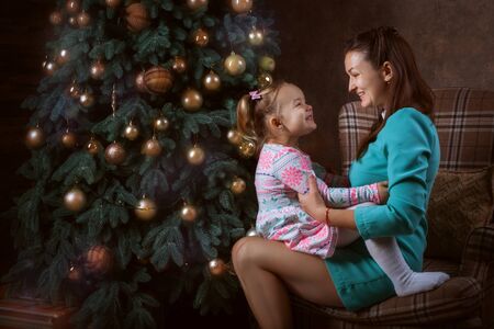 Mom and daughter near a Christmas tree. They are laughingの写真素材