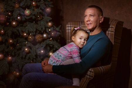 Father and daughter in the living room near the Christmas treeの写真素材