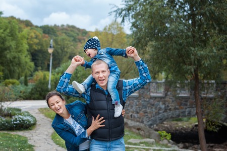 Young family walking in the park. They hug and laugh.