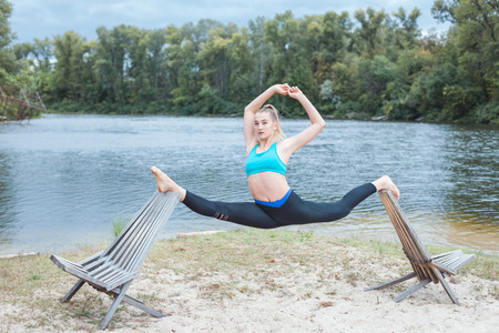 Girl is doing sports near the river. She does the splits on sunbedsの写真素材