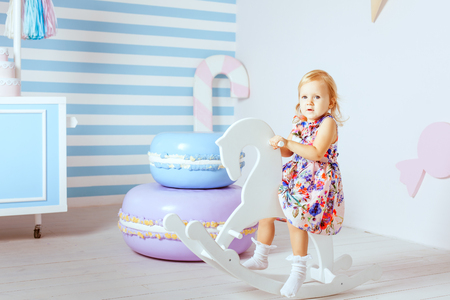 Cute little girl is riding a wooden horse.の写真素材