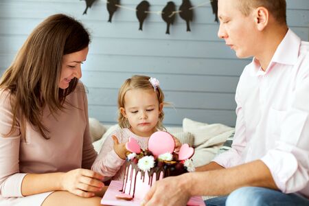 Parents with a little daughter. Girl is trying the cake with her fingerの写真素材
