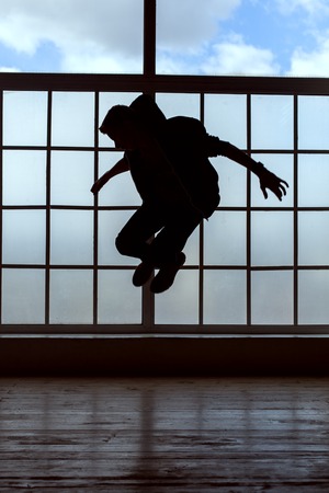 Silhouette of a young man. He makes a jump in the danceの写真素材
