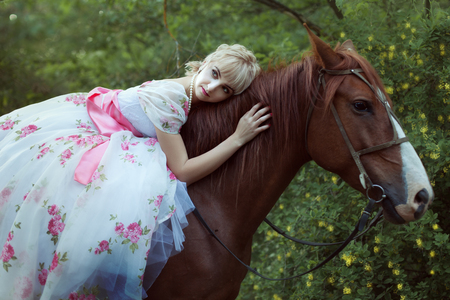 Beautiful woman in retro dress lies on horse.の写真素材