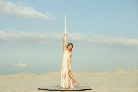 Young woman in a dress stands near a pylon in the desert.の写真素材