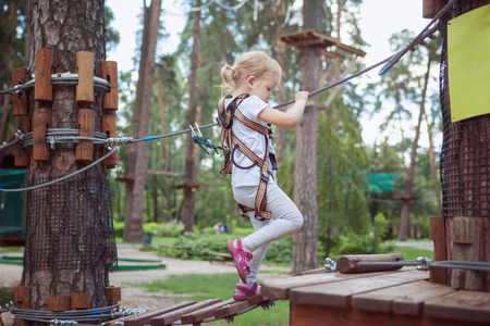 Active rest. Little girl having fun in the rope park.の写真素材