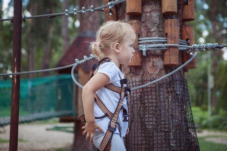 Girl in rope park. She rests between sections of the road.の写真素材