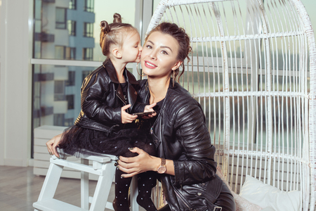 Portrait of a young mother and her daughter. Girl kisses mom on cheeks.の写真素材