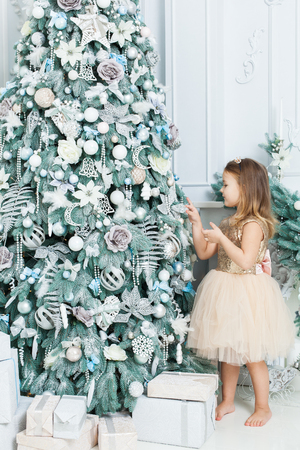 Little girl in beautiful dress decorates the Christmas tree.の写真素材