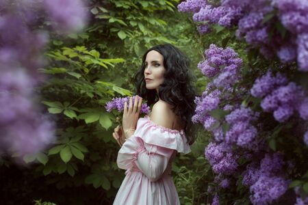 Portrait of a beautiful young woman in the spring garden among lilac blossoms.の写真素材