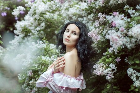 Beautiful brunette woman in spring garden among blooming lilac.の写真素材