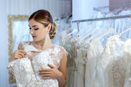 Beautiful young woman measures wedding dresses in a bridal salon.の写真素材